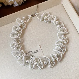 Close-up detail of an elegant white ruffled glass bead necklace with pearl accents