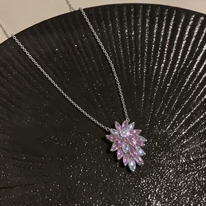 Detailed macro view of a sparkling zircon flower pendant necklace on a black tray