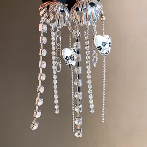 Close-up detail of metal heart pendant necklace with shimmering crystal tassels