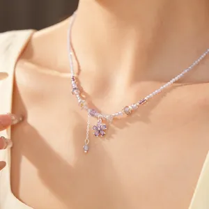 Detail view of an elegant purple beaded necklace featuring a sparkling zircon flower pendant on neck