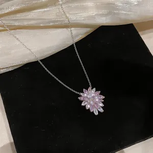 Detailed macro shot of a blooming pink zircon flower pendant on a silver necklace