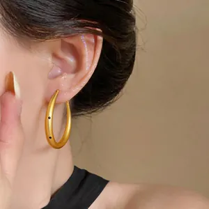 Primer plano de pendientes de aro de oro cepillado minimalistas con detalles de puntos negros