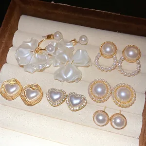 Elegant pearl and heart stud earring set with gold accents in a luxury display box.