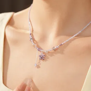 Close-up of purple beaded necklace with cubic zirconia flower pendant on model.