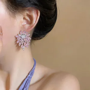Detailed close-up of sparkling pink zircon flower stud earrings on a model.