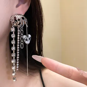 Detailed view of silver tassel earrings with rhinestone chains and heart pendant