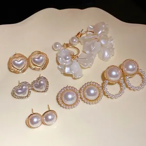 Elegant silver needle pearl earrings set with heart and round designs on beige plate