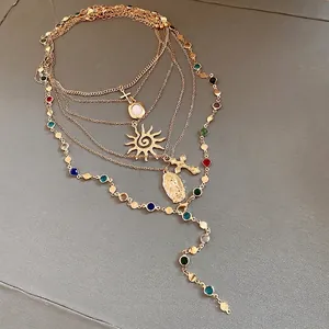 Elegant layered gold necklace featuring sun and cross pendants with colorful stones