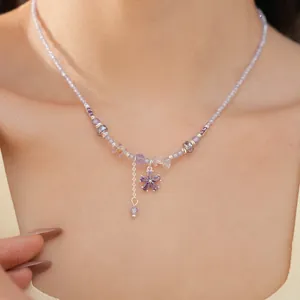 Detail view of a vacation style purple beaded necklace with a zircon flower pendant.