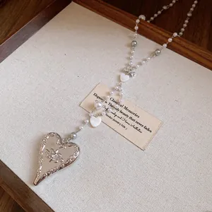 Detailed macro view of the ornate engraved silver heart pendant with pearl bead chain.