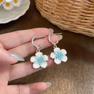 Primo piano di orecchini a fiore blu e bianco su cerchi a C in argento