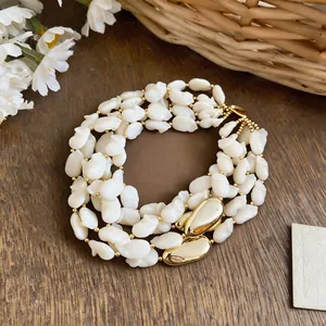 Vue détaillée d'un collier à plusieurs rangs en coquillage blanc avec accents dorés.