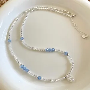 Dainty beaded pearl necklace with blue crystals and a sparkling rectangular pendant.