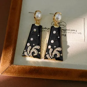 Close-up of vintage black enamel earrings featuring pearls and sparkling rhinestones