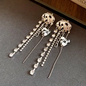 Detailed macro of silver-toned shell earrings with crystal tassels and floral heart