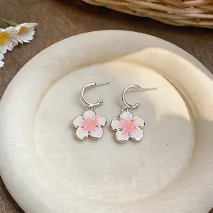 Primo piano di ciondoli a fiore in smalto rosa e bianco su orecchini a cerchio a forma di C