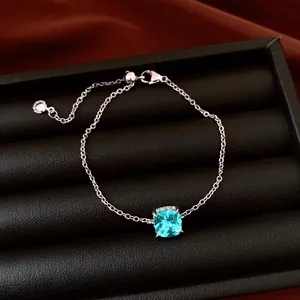Close-up of a silver chain bracelet featuring a sparkling square blue zircon stone