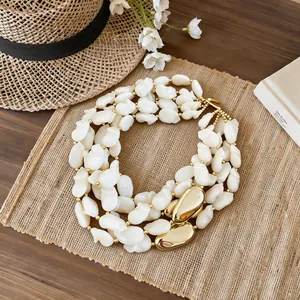Vue détaillée d'un collier de perles blanches multicouche aux accents dorés chics