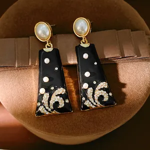Close-up of vintage enamel drop earrings with intricate pearl and rhinestone floral details.