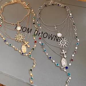 Detailed view of gold and silver layered necklaces with sun, cross, and portrait charms