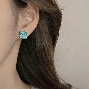Close-up view of a minimalist square-cut light blue zircon earring worn on a model's ear