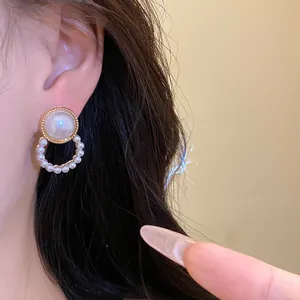 Close-up detail of elegant pearl drop earring worn on ear with gold setting.