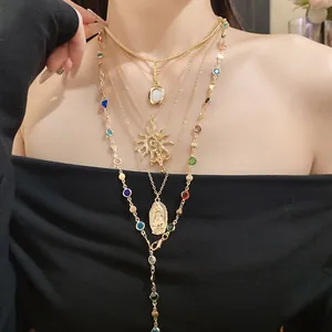 Detailed shot of layered gold necklace featuring sun, cross, and Virgin Mary medal pendants
