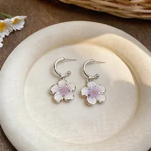 Primo piano di orecchini a cerchio a C con fiori in smalto viola e perni in argento S925.
