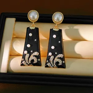 Detailed macro view of vintage black enamel dangle earrings with pearls and rhinestones