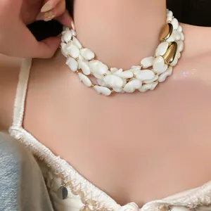 Gros plan d'un collier multi-rangs en nacre blanche et métal doré sur le cou