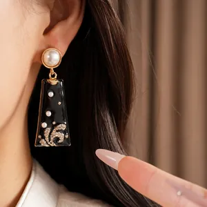 Close-up view of vintage black enamel earring with pearls and sparkling crystal details