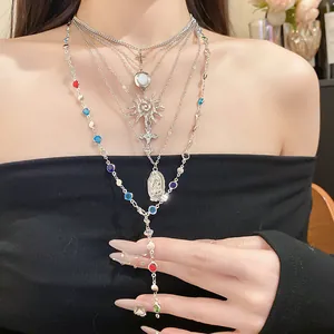 Elegant silver layered necklace set featuring cross, sun and icon pendants worn by model