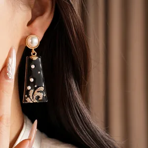 Close-up of vintage pearl and black enamel earrings with rhinestone details