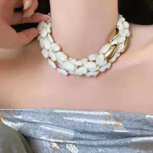 Vue macro d'un collier luxueux à plusieurs rangs avec coquillages blancs et métal doré