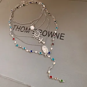 Detailed macro view of silver multi-layer necklace with sun, cross pendants and colorful gems