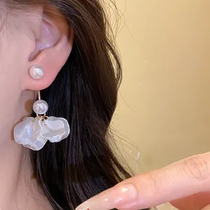 Close-up view of elegant pearl earrings featuring frosted white petals on a silver needle base