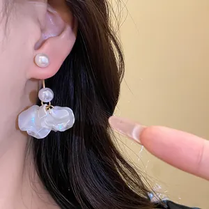 Exquisite detail view of elegant white petal pearl drop earrings shown on a model's ear