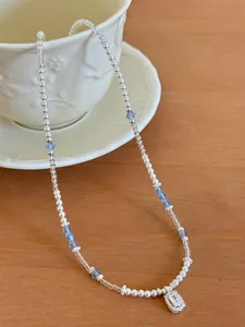 Close-up of elegant beaded necklace with pearls, blue crystals and sparkling pendant