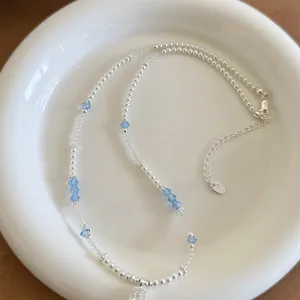Close-up detail of beaded pearl necklace with elegant light blue crystal accents and pendant