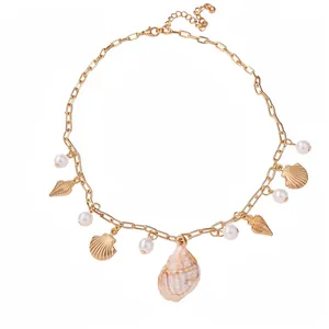 Collana a maglie dorate decorata con perle e ciondoli a conchiglia su sfondo bianco