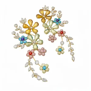 Pendientes largos de flores con cristales coloridos y marco dorado sobre fondo blanco