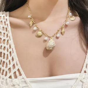Dettaglio di una collana dorata con ciondoli di conchiglia e perle per le vacanze.
