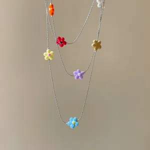 Detailed macro view of colorful resin flower charms on a layered silver chain necklace.