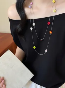Detail showing colorful resin flower charms on a thin silver chain necklace.