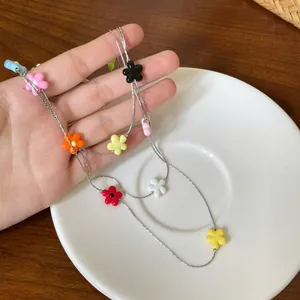 Close-up of a colorful resin flower beaded necklace on a white ceramic saucer, summer style.