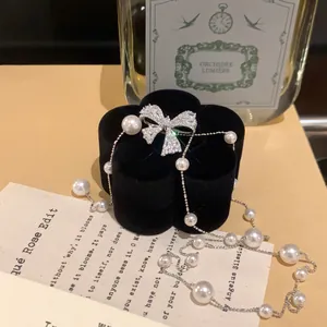 Gros plan du pendentif nœud en zircon et collier de perles sur boîte à bijoux en velours