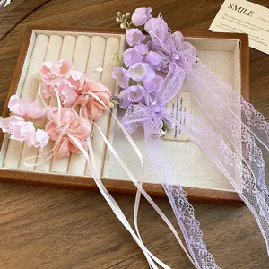 Gros plan de barrettes de muguet roses et mauves avec d'élégantes franges en dentelle.