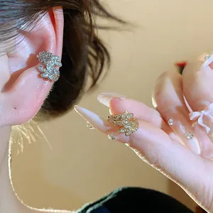 Dettaglio ravvicinato dei polsini orecchio spiga di grano con zirconi oro e argento.