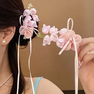 Détail d'une pince à cheveux muguet rose avec strass et longs glands de ruban soyeux
