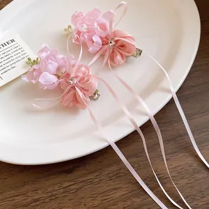 Détail de pinces à cheveux muguet rose avec de longs rubans et des cristaux brillants